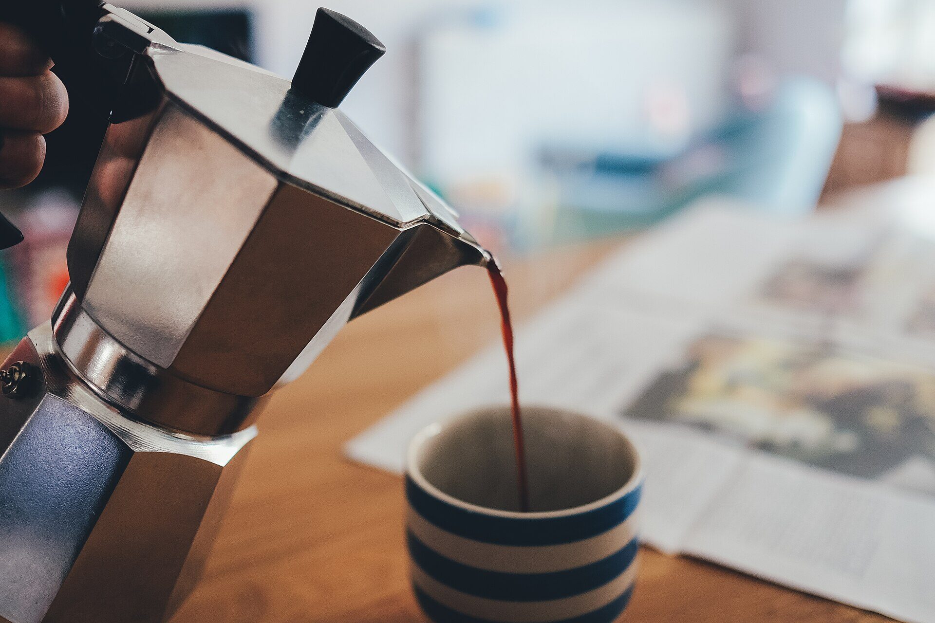 Cafetera de acero sirviendo café recién hecho en una taza