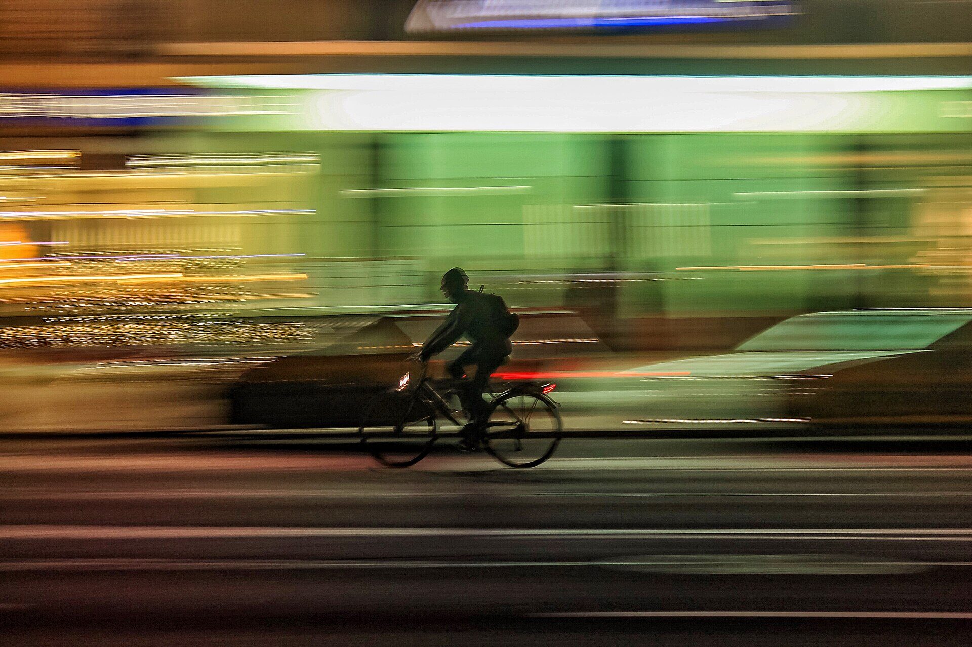 Ciclista urbano de noche con luces de la ciudad en movimiento